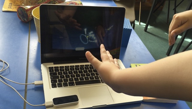 Child's hand waving over a leap motion controller